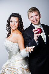 Image showing groom taking red apple from young beautiful bride