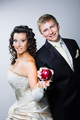 Image showing groom taking red apple from young beautiful bride