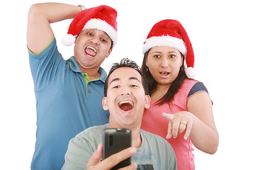 Image showing Young friends looking shocked at cell phone with Christmas hat