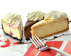 Image showing slices of cheesecakes with fork and napkin 