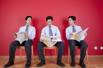 Image showing Three businessman reading a newspaper