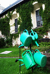 Image showing four green watering can in the churchyard