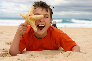 Image showing Laughing boy with starfish on the beach
