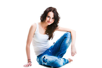 Image showing pretty woman in blue jeans sitting on white floor