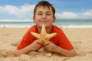 Image showing Boy on beach holding a sea star