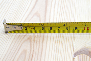 Image showing Tape measure on wood background 