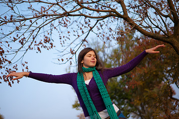 Image showing Young girl with closed eyes and raised arms 