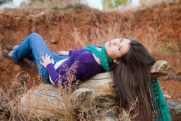 Image showing Shot of a young woman lying on log 