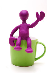 Image showing Purple puppet of plasticine sitting on cup