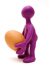 Image showing Purple puppet of plasticine holding one egg