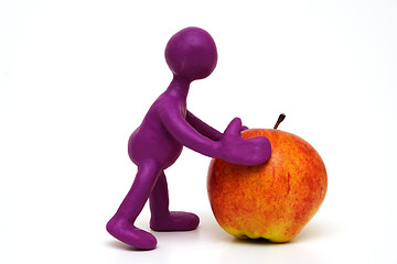 Image showing Purple puppet of plasticine pushing done apple