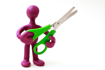 Image showing Purple puppet of plasticine holding green scissors