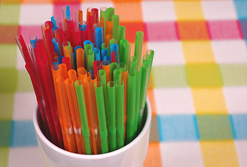 Image showing Colorful straws in white glass on checkered mat