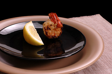Image showing Shrimp and lemon on black plate
