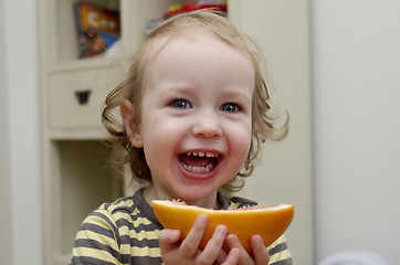 Image showing little girl laughing and eating grapefruit