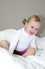 Image showing little girl sitting on a bed and smiling