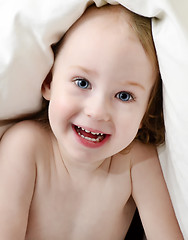 Image showing little girl looking out from under blanket