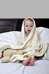 Image showing little girl in a towel after a shower resting on a bed