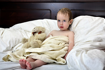 Image showing little girl in a towel after a shower resting on a bed