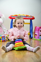 Image showing little girl in a room with toys, playing with color pyramid