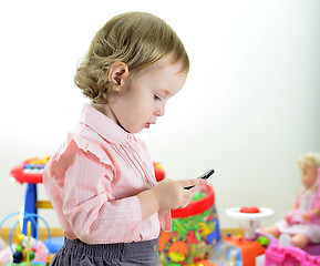 Image showing little girl standing with mobile phone in room with toys