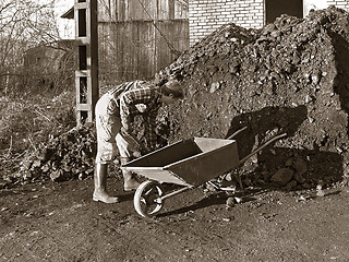 Image showing worker loads coal on wheelbarrow 