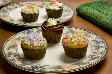 Image showing Ornately decorated cupcakes on plates