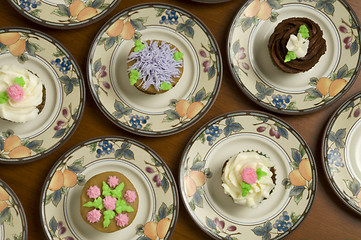 Image showing Ornately decorated cupcakes on plates