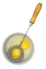 Image showing Crude eggs in a plate and mixer with the wooden handle.