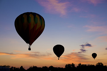 Image showing Hot-air balloons floating against a reddish dawn sky