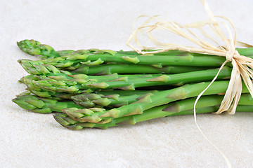 Image showing Fresh organic asparagus bunch tied with raffia on a tile counter