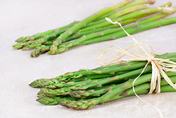 Image showing Two bunches of fresh asparagus on tile counter top.