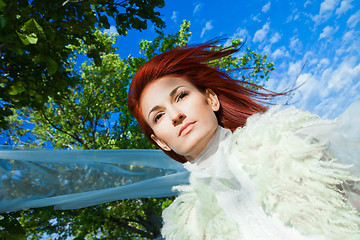 Image showing beautiful woman in white against blue sky and green trees