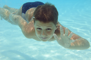Image showing Boy swimming underwater in swimming pool 