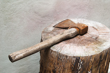 Image showing The old rusty axe lays on a log