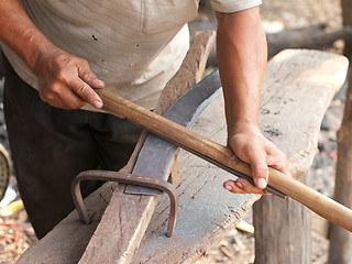 Image showing Blacksmith sharpening a sickle