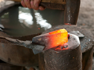 Image showing Blacksmith forging an ax