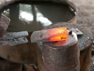 Image showing Red hot head of ax at a blacksmith's workshop