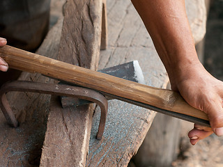 Image showing Blacksmith sharpening an ax