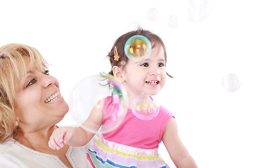 Image showing Aunt and a little girl enjoy looking at bubbles floating in the 