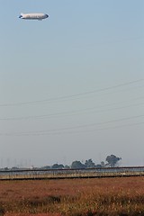 Image showing Blimp floating above the marshland and power lines