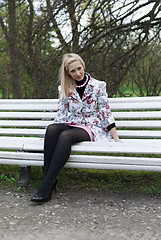 Image showing blonde girl sitting on a park bench 