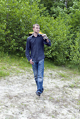 Image showing man walks through the woods with his guitar