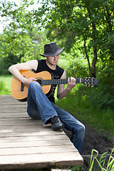 Image showing man playing guitar in the woods