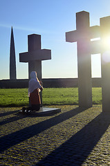 Image showing Girl praying at the Crosses at sunset