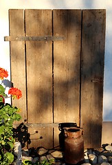 Image showing Milk jug in front a wooden gate