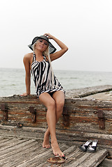 Image showing girl in a hat sitting on a broken ship at sea