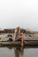 Image showing girl in a hat sitting on a broken ship at sea