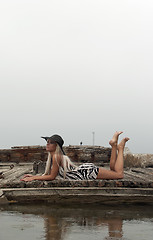 Image showing girl in a hat sitting on a broken ship at sea