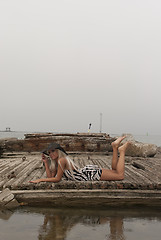 Image showing girl in a hat lying on a broken ship at sea